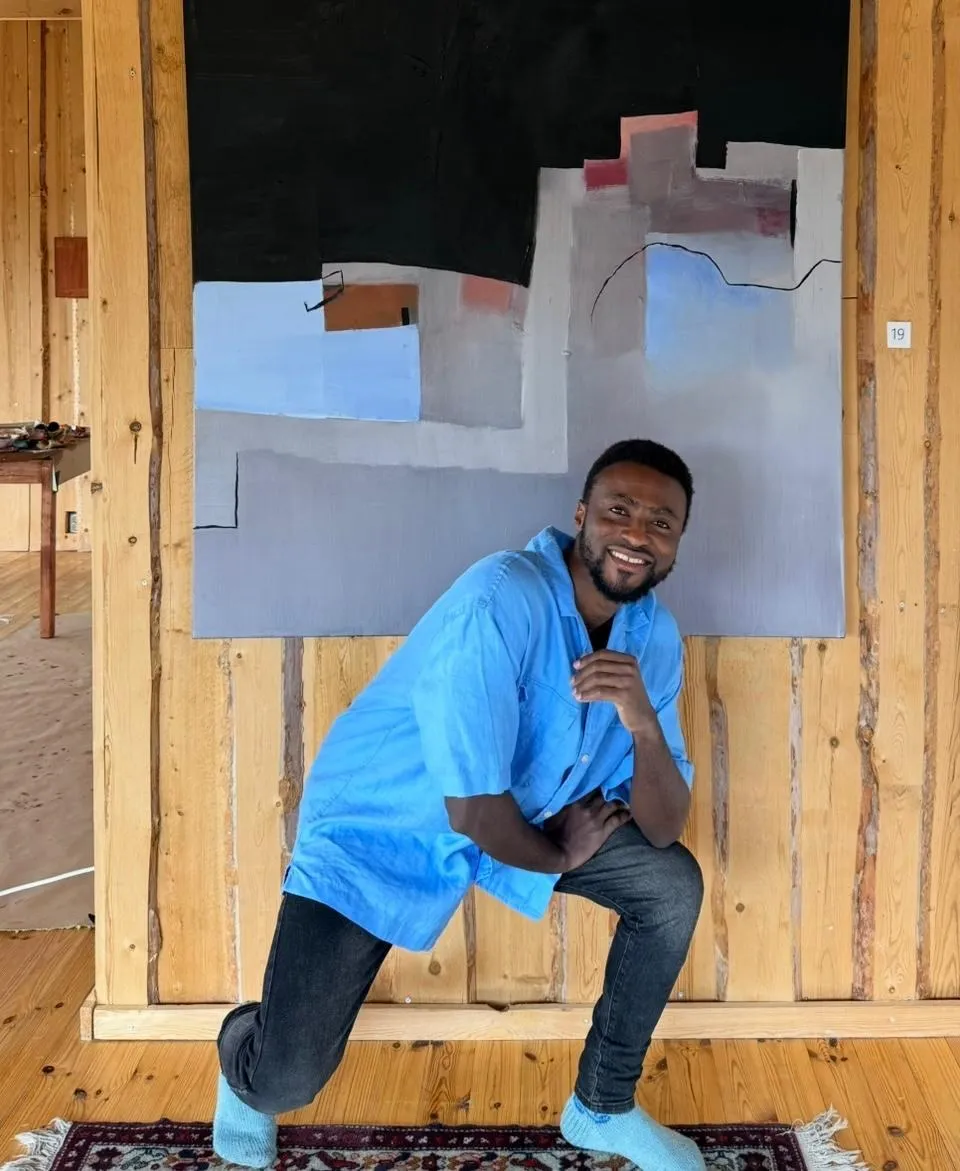 An artist in front of an abstract painting inside the wooden gallery at Manna BB, Lapland